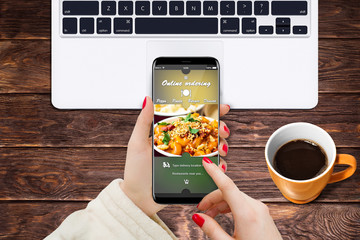 Girl at home ordering vegetarian food while sitting at desk in front of laptop and coffee