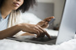 © JGI/Jamie Grill/Blend Images - African American woman laying in bed online shopping with laptop