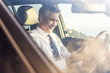 © Adam Hester/Blend Images - Smiling Caucasian businessman sitting in car texting on cell phone