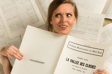 Wall Mural - Young caucasian hipster woman with music shirt lies on sheet music in a room