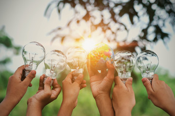 Wall Mural - children show hand with light bulb and world toy concept solar energy