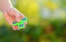 Boy Playing With Green Spinner Outdoors  On The Bright Bokeh