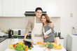 © makistock - Happy asian couple following recipe on digital tablet when cooking