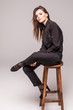© F8  \ Suport Ukraine - Portrait of a happy cheerful woman in black sitting on the chair and looking at camera over gray background