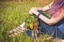 Woman Legs Sitting In Grass On Summer Meadow
