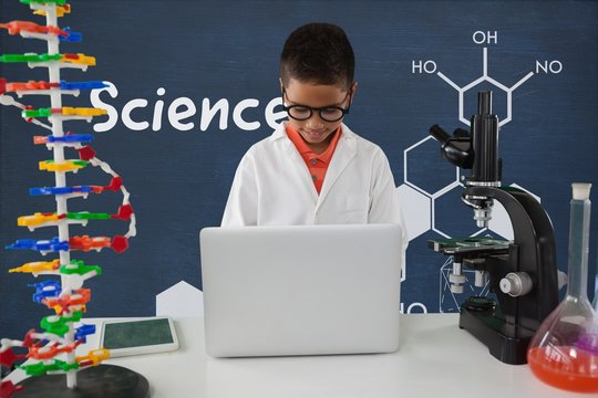 Student boy at table using a computer against blue blackboard wi