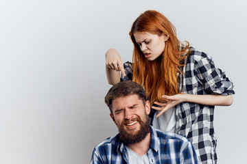 Young beautiful woman with a man with a beard on a light background, relationship, quarrel