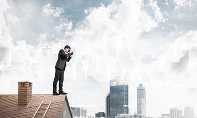 Businessman standing on roof and looking in binoculars. Mixed me