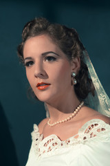 Vintage 1940s bride in white dress and pearl necklace. Studio head shot.