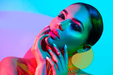 Fashion model woman in colorful bright lights posing in studio, portrait of beautiful sexy girl with trendy makeup and manicure