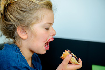 Wall Mural - funny girl eating bread roll with marmelade