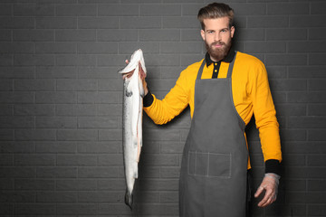 Poster - Handsome seller holding fresh fish on gray wall background