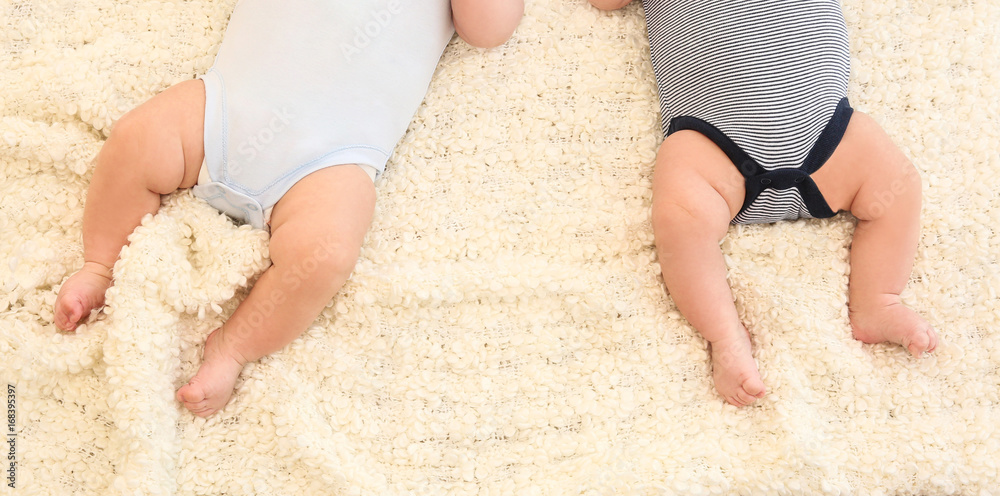 Cute little babies lying on bed at home