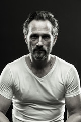 Poster - Black and white portrait of brutal beardy man. Monochrome photo of mid aged male on black backdrop.