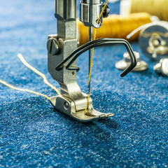Wall Mural - background 1:1 size of close up look sewing machine jeans parts as follows needle, presser foot, threads, bobbin, replacement button on denim fabric.