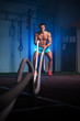 © pavel_shishkin - Muscular fitness man working out with battle ropes