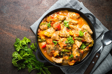 Wall Mural - Stew meat with vegetables in tomato sauce. Top view on dark stone table.