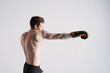 © Anatoliy Karlyuk - Determination, endurance, strenght, fitness, sports and people. Confident shirtless young Caucasian man boxer wearing boxing gloves, exercising in studio or gym, preparing for fight or competition
