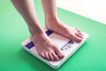 Female feet standing on mechanical scales for weight control. Concept of slimming and weight loss