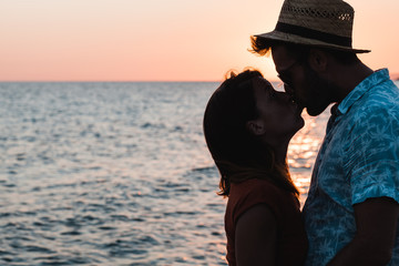 Wall Mural - Young couple hugging and kissing on a beach in sunset