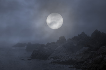 rocky coast in a foggy full moon night