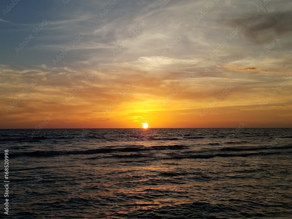 Sunset on an island with cloudscape over the water
