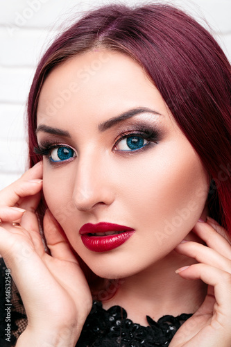 A Chic Girl Or Woman With A Fine Make Up Stands On A White Wall