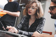 © leonidkos - Young and beautiful business woman shows on a modern smartphone a startup analysis of her coworking team. Photo work in loft space and use of digital devices and gadgets