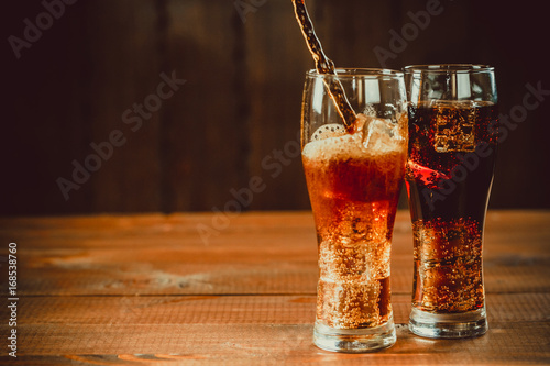 Stampa su Tela Beautiful cold drink of Cola with ice cubes with a boiler straws in glasses on w