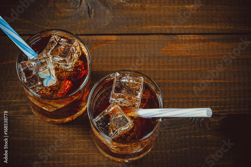 Fotografia Beautiful cold drink of Cola with ice cubes with a boiler straws in glasses on w