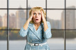 Portrait of astonished mature woman. Closeup portrait of a terrified white-skin woman looking shocked surprised in full disbelief hands on head, office window background.