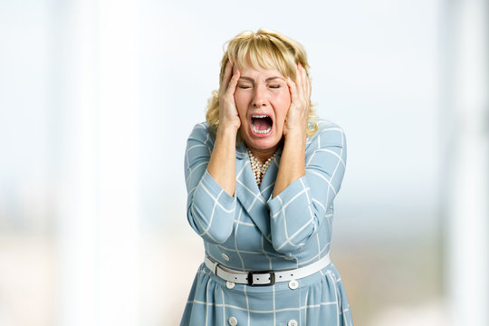 mature woman screaming in despair. close up shot of stressed and shocked white-skin woman screaming 