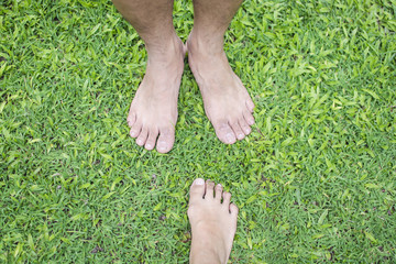 Bare foot of Asian woman and man standing over green grass for relaxing, couple and together concept