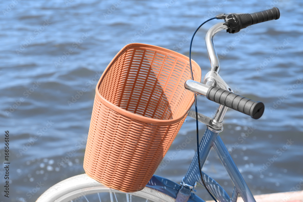 Bicycle with wicker basket and river on background
