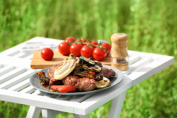 Poster - Grilled tasty beefsteaks and vegetables on white table outdoors