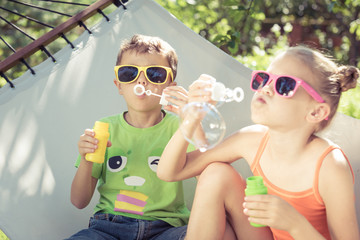 Wall Mural - Two happy children lie on a hammock and play with soap bubbles