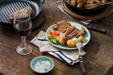 Wall Mural - Grilled steak with potatoes, salad on wooden table with wine