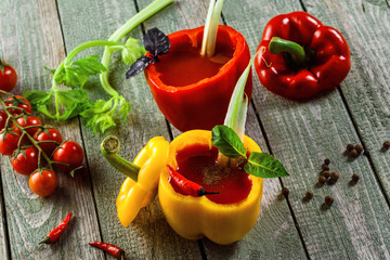 Classic bloody mary in in yellow and red sweet bell peppers a wooden table. Alcoholic drink made of tomato juice, vodka, pepper, salt, lemon juice, celery and other flavorings. Top view shot.