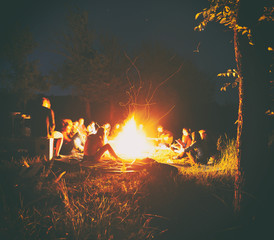 Wall Mural - The company of young people are sitting around the bonfire and singing songs