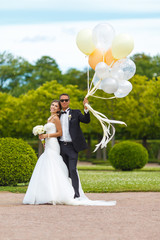 Merry newlyweds in the park with balloons
