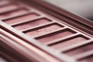 Wall Mural - Eye shadow palette in rose gold and nude colors closeup. Makeup cosmetics. Selective focus.