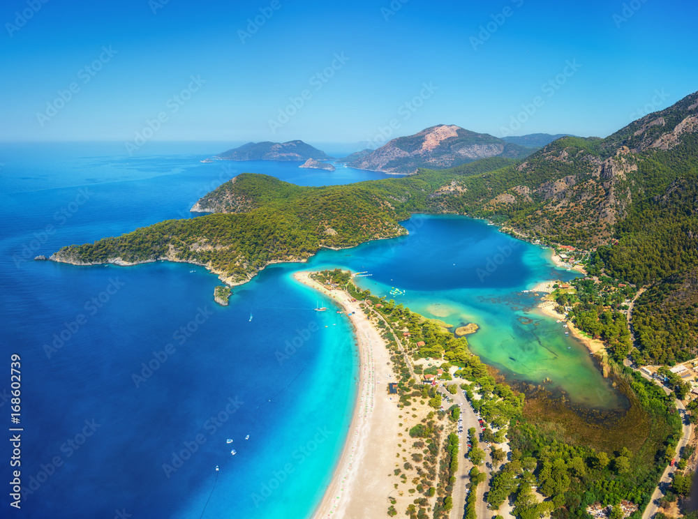 Amazing aerial view of Blue Lagoon in Oludeniz, Turkey. Summer landscape with mountains, green forest, azure water, sandy beach and blue sky in bright sunny day. Travel background. Top view. Nature - obrazy, fototapety, plakaty 