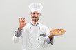 Chef holding pizza and showing ok sign.