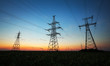 Silhouette of electricity pylons and high-voltage power lines on the field at sunset. Wire electrical energy at sunrise