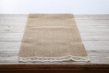 Canvas napkin with lace. Burlap hessian sacking on white wooden table background top view