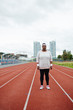 © pressmaster - Young plump woman in activewear standing on one of racetracks