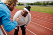 © pressmaster - Oversized woman listening to her trainer consultation during workout at stadium