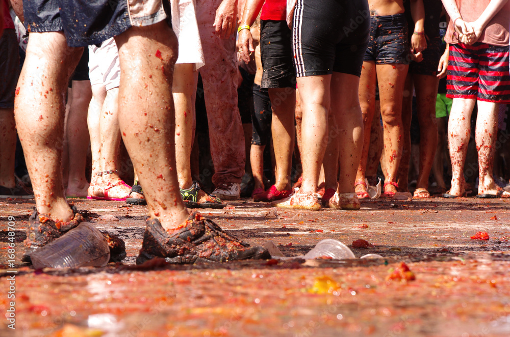 Tłum ludzi bawiących się na La Tomatina. Ujęcie nóg.  - obrazy, fototapety, plakaty 
