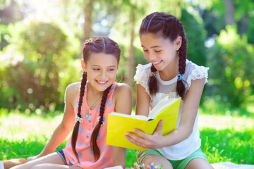 Happy hispanic girls drawing and studying in park