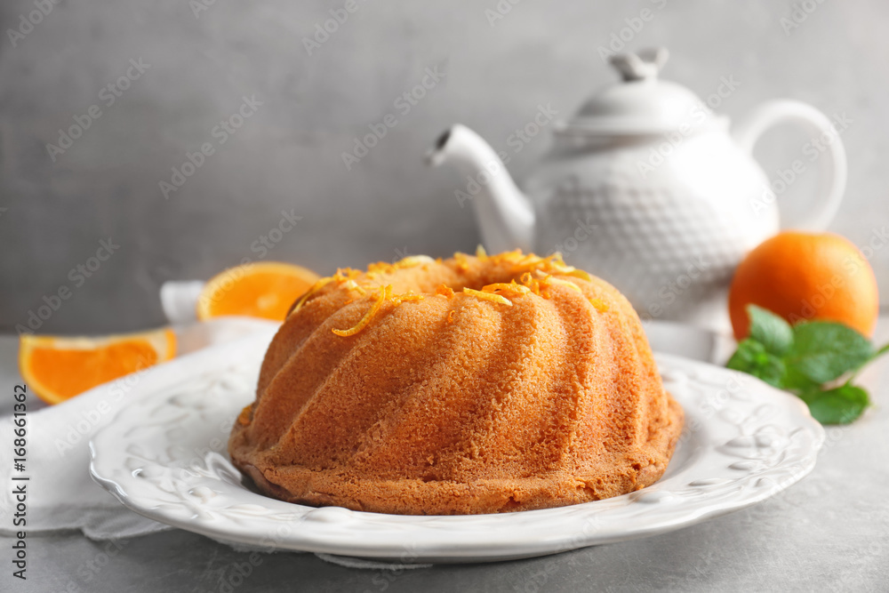 Plate with delicious citrus cake and orange zest on light table